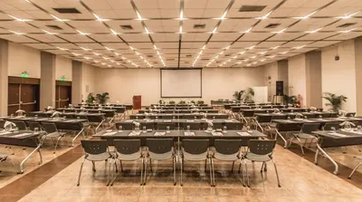 a large room with tables and chairs and a screen at Hotel Las Dunas in Ica