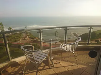 a balcony with two chairs and a table and the ocean at Malecón in Lima