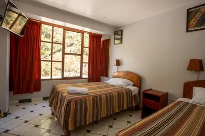 a hotel room with two beds and a window at Hostal La Payacha MachuPicchu in Machu Picchu
