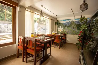 a dining room with a table and chairs and a man at Hostal La Payacha MachuPicchu in Machu Picchu
