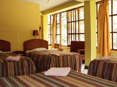 a hotel room with two beds and windows at Hostal La Payacha MachuPicchu in Machu Picchu