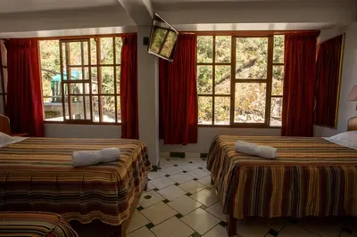 two beds in a room with red curtains and windows at Hostal La Payacha MachuPicchu in Machu Picchu