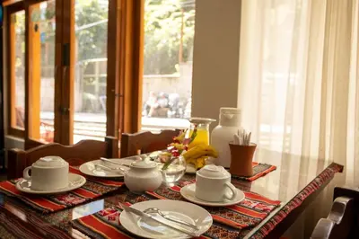 a table with plates and dishes on it with a window at Hostal La Payacha MachuPicchu in Machu Picchu