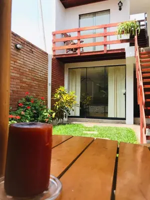 a drink sitting on a wooden table in front of a house at Hospedaje Casa de Playa Arica in Lurín