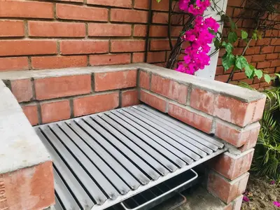 a bench sitting against a brick wall with flowers at Hospedaje Casa de Playa Arica in Lurín