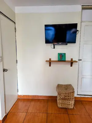 a living room with a flat screen tv on a wall at Habitación con dos camas, baño privado, terraza y cocina compartida en Miraflores in Lima