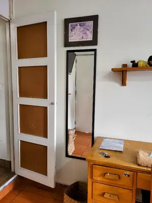 a mirror on a wall next to a wooden table at Habitación con dos camas, baño privado, terraza y cocina compartida en Miraflores in Lima