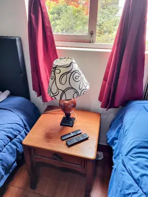 a table with a lamp on it next to two beds at Habitación con dos camas, baño privado, terraza y cocina compartida en Miraflores in Lima