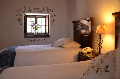 a bedroom with two beds and a mirror and a phone at Unaytambo Boutique Hotel Cusco in Cusco