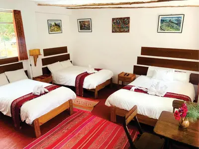 a room with three beds and a table at Inka Khawarina Tambo Lodge in Ollantaytambo