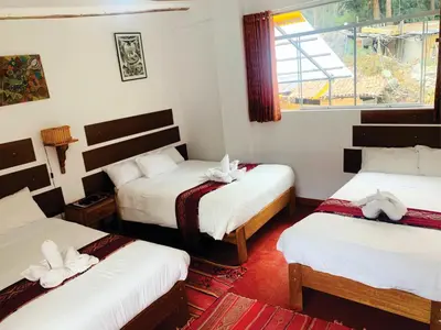 a room with three beds and a window at Inka Khawarina Tambo Lodge in Ollantaytambo