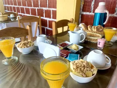 a table topped with bowls of food and orange juice at Inka Khawarina Tambo Lodge in Ollantaytambo