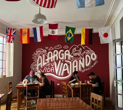 people sitting at tables in a restaurant with flags on the wall at Great Partners hostel in Lima