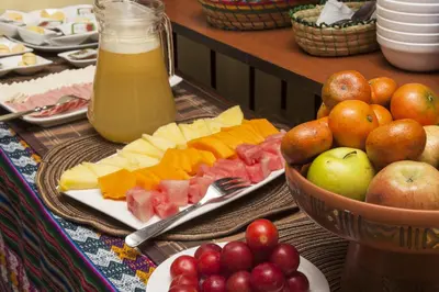 a table with a plate of fruit and a bowl of juice at Casona les Pleiades in Cusco