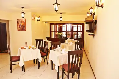 a dining room with tables and chairs and a television at Apart Hotel Caminos del Inca in Lima