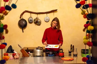 a woman standing in a kitchen holding a box of food at KACLLA, The Healing Dog Hostel in Lima