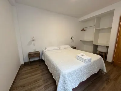 a bedroom with a white bed and a wooden floor at Betania in Paracas