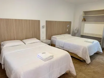 two beds in a hotel room with white sheets at Betania in Paracas