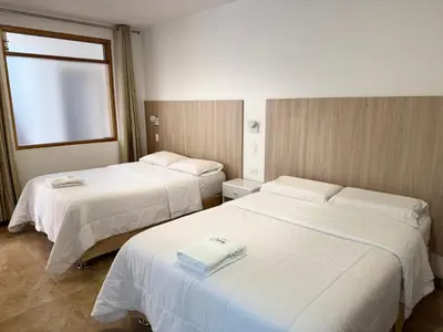 two beds in a hotel room with a window at Betania in Paracas