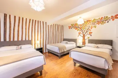 a bedroom with two beds and a tree on the wall at Tika Wasi Casa Boutique in Cusco