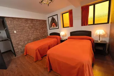 two beds in a room with orange sheets at Tika Wasi Casa Boutique in Cusco