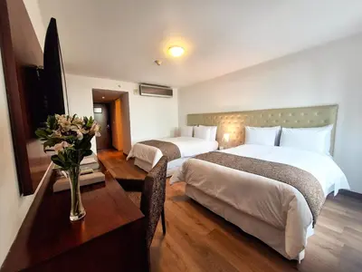 a hotel room with two beds and a table with flowers at NM Lima Hotel in Lima