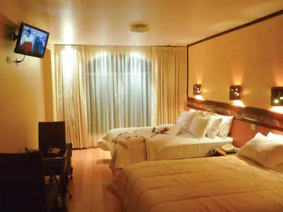 a hotel room with two beds and a flat screen tv at Hotel Taypikala Machupicchu in Machu Picchu