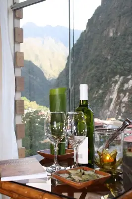a table with glasses and a bottle of wine at Hotel Taypikala Machupicchu in Machu Picchu