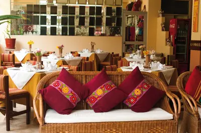 a wicker chair with red pillows in a restaurant at Hotel Taypikala Machupicchu in Machu Picchu