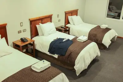a hotel room with three beds with towels on them at Hotel Unu in Huancayo