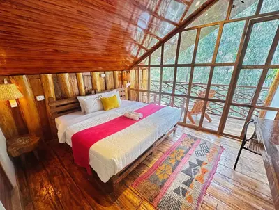 a bedroom with a bed in a room with windows at Eco Quechua Lodge in Santa Teresa