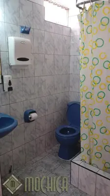 a bathroom with a blue toilet and a shower curtain at Hostal Residencial Mochica in Lima