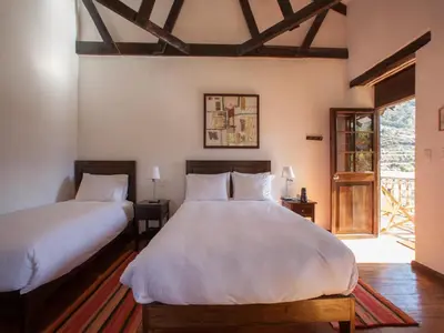 two beds in a room with a window at El Albergue Ollantaytambo in Ollantaytambo