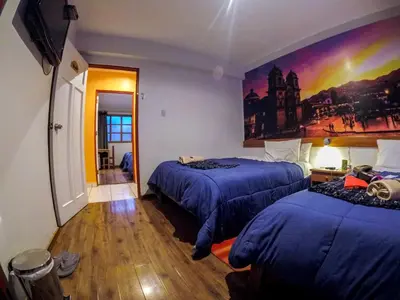 a bedroom with two beds and a painting on the wall at Net House Cusco in Cusco