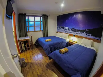 a room with two beds and a large painting on the wall at Net House Cusco in Cusco