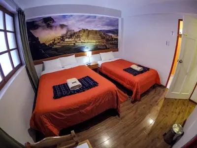 a room with two beds with a painting on the wall at Net House Cusco in Cusco