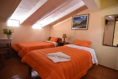 two beds in a room with orange sheets at Tambo Cusco Inn in Cusco
