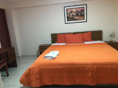 a bedroom with a bed with an orange blanket at Tambo Cusco Inn in Cusco