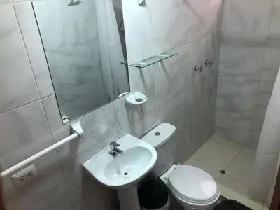 a white bathroom with a toilet and a sink at Tambo Cusco Inn in Cusco
