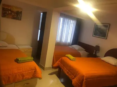 a bedroom with two beds with orange sheets at Tambo Cusco Inn in Cusco