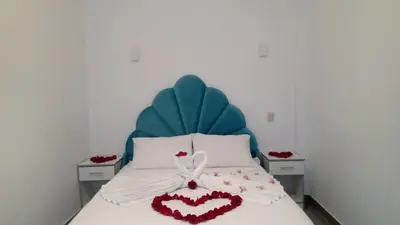a bedroom with a bed with a blue headboard and a heart pillow at AQUAMARINE PARACAS Beach Hostal in Paracas