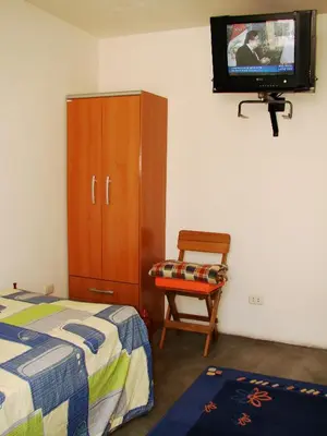 a bedroom with a bed and a cabinet and a tv at Posada Peregrinus in Lima
