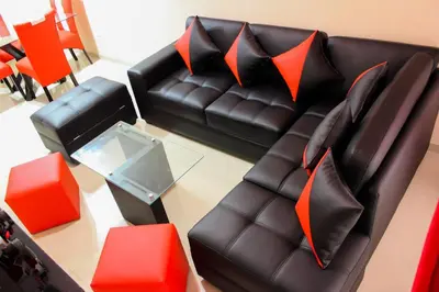 a living room with a black leather couch and orange pillows at Peruvian Apartment in Lima