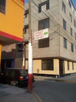 a street sign on a pole in front of a building at Sunset Hostel Airport in Lima