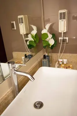 a bathroom with a sink and a mirror and flowers at SM Hotel in Lima