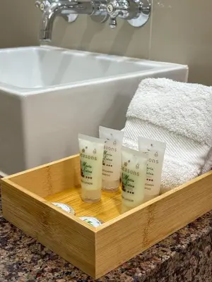 a wooden tray with four moisturizing candles in front of a sink at Hotel María Luisa in Lima
