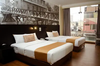 two beds in a hotel room with a large window at Hotel María Luisa in Lima