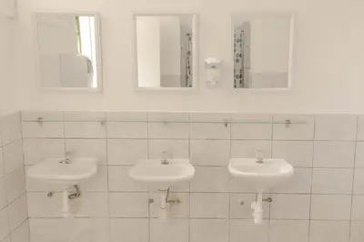 two sinks in a white tiled bathroom with mirrors at 1900 Backpacker's Hostel in Lima