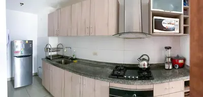 a kitchen with wooden cabinets and a sink and a refrigerator at Condominio Uptown de 2 dormitorios in Lima