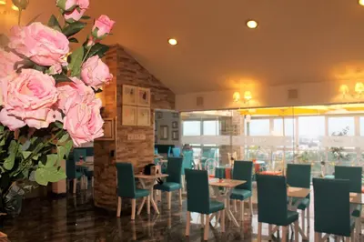 a restaurant with pink roses and tables and chairs at Hotel Vila Santa in Lima